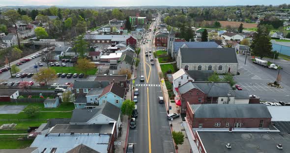 Small town America. Aerial shot of street through city with church and buildings. Rising aerial esta alt