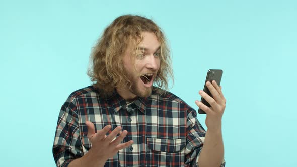 Slow Motion of Attractive Blond Guy with Beard Reading Smartphone Screen with Surprised and Happy