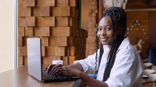 Young African American Woman Using Laptop Computer in Cafe alt