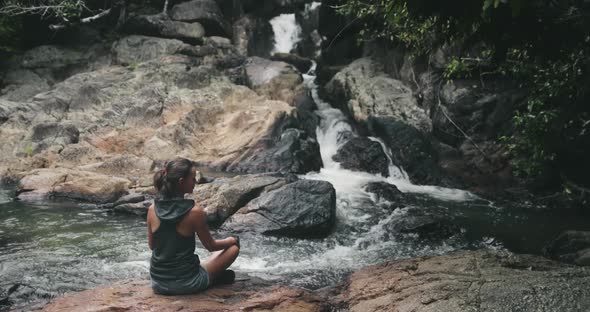 Thai Waterfall Woman Relaxing Pose Asana on Boulder of Jungle River Shore