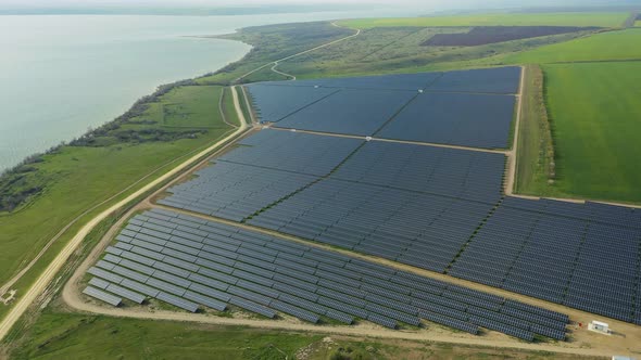 Aerial View of a Solar Panel Farm with Rows of Panels Drawing Energy From the Sun By the Lake alt