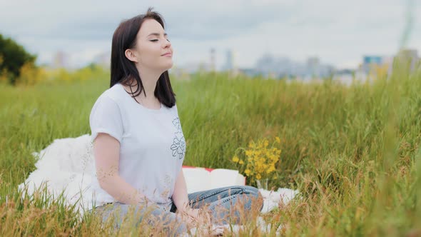 Carefree Caucasian Woman Young Girl Meditating in Bliss Yoga Practice in a City Park on Green Grass alt