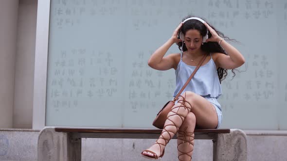 Woman Sitting on Urban Bench Listening To Music and Dancing