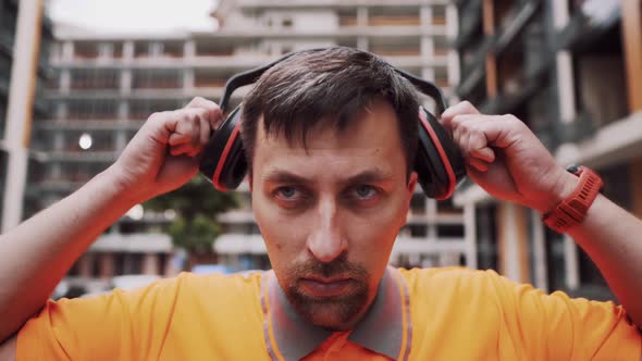 Man Wearing Safety Equipment Hearing Protection. Worker Wearing Noise Cancelling Ear Defenders or alt