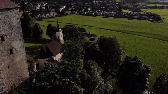 Medieval Fortress Surrounded By Lush Vegetation Near Township In Kaprun, Austria. - Aerial Shot alt