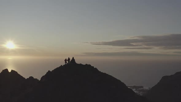 Group Of Young On Top Of A Mountain In The Light Of The Sunset