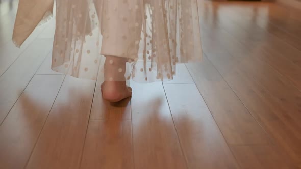 A Woman Walks Barefoot on the Parquet in a Sunny Room alt