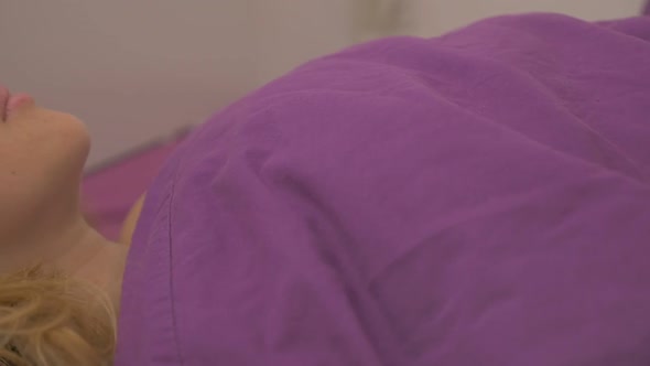 Woman relaxing in the bed with purple sheets slow-mo   1080p HD panning  video - Beautiful blond wom