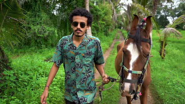 Young handsome man with brown horse. alt