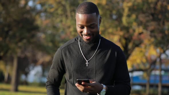African-American Man Chatting in Smartphone, Outdoors