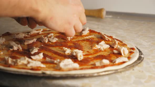 Male Hands Putting Pieces of Boiled Chicken on the Dough in Metal Form at Kitchen alt