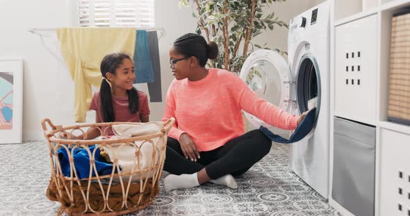 Joyful Woman Spends Time Together with Daughter While Doing Household Chores They Sort Laundry alt