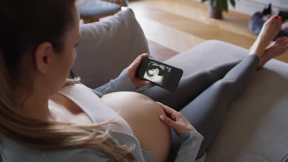 Pregnant woman looking on medical scans on the smartphone. Shot with RED helium camera in 8K alt