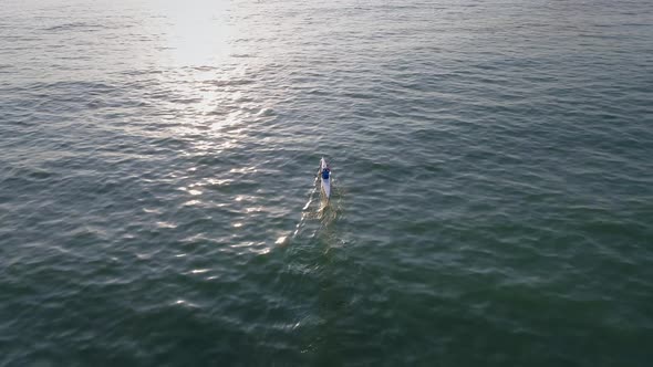 Aerial view above of a man paddling kayak in the sea. alt