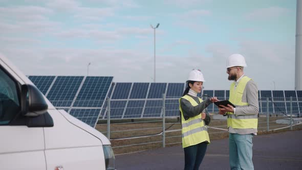 Ecological Engineers Use Digital Tablet and Talk at the Solar Panel Field