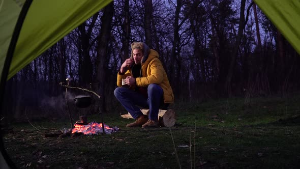 A Man Near a Campfire in the Forest alt