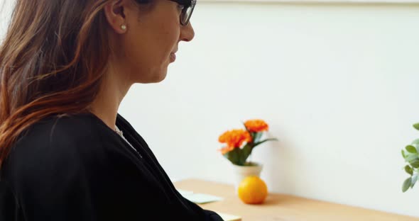 Female executive sitting at desk and using laptop alt