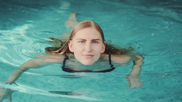 Close Up of Stunning Blonde Woman Swimming in Pool to the Camera