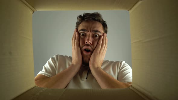 Bottom View Amazed Man Looks Into the Empty Box From the Inside alt