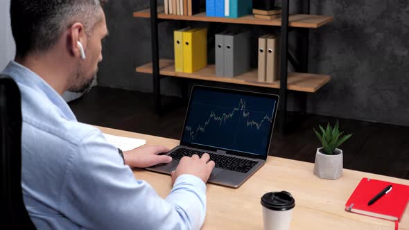Man Professional Stock Trader Broker Uses Laptop with Stock Exchange Chart alt