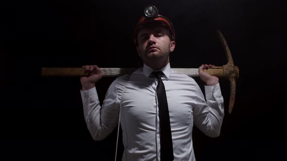 Brutal Caucasian Man with Serious Look Stand on Black Background with His Hand Holding a Pickaxe alt