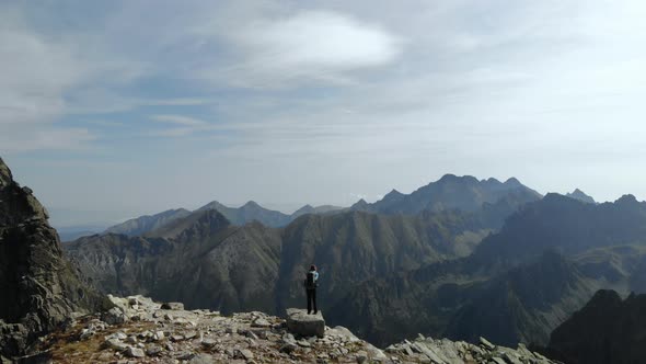 Girl Hiker with Backpack Standing on Top of a Rock Looking at Tatra Mountains alt