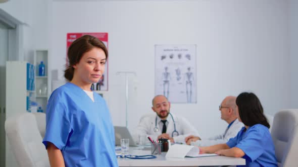 Portrait of Young Nurse Standing in Front of Camera Smiling alt