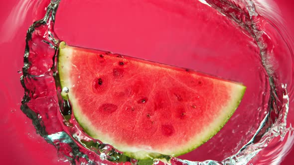 Super Slow Motion Shot of Falling Fresh Watermelon Slice Into Water on Red Background at 1000Fps. alt