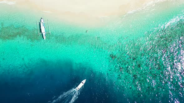 Touring boats tracing and foaming through deep blue sea sailing toward shallow turquoise lagoon near alt