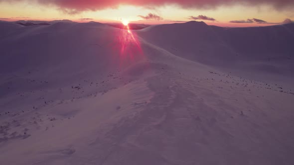 Drone Flying Over Winter Mountain Valley During Pink Sunset