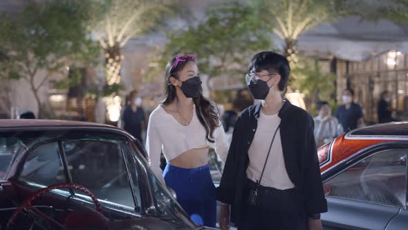 A Couple Wearing Black Mask Was Standing in Front of a Beautiful Car in a Corner Looking at the Car alt