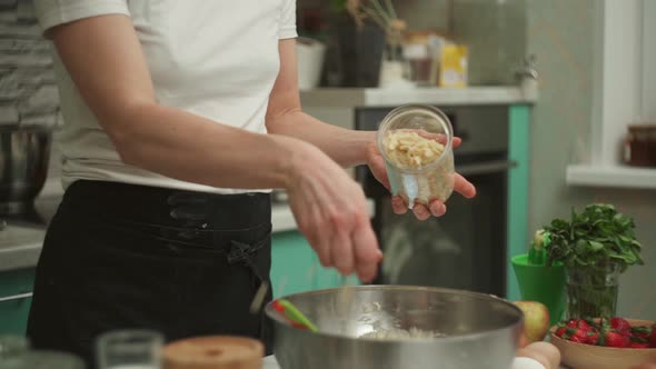 Crop Housewife Adding Almond Flakes Into Bowl with Raw Dough