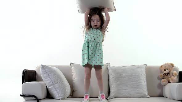 Playful young girl spoils and throws pillows in slow motion