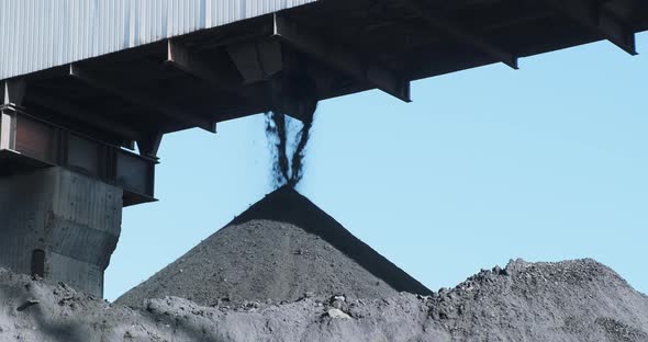 Black Coal Poured Into Huge Mineral Pile From Conveyor Against Blue Sky alt