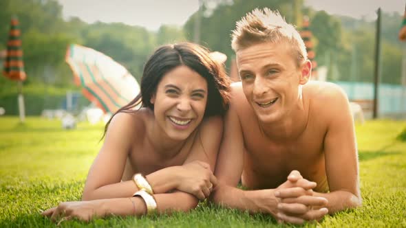 Beautiful Young Romantic Couple Lying Down on the Grass Having Fun at Water Park in Summer Day Dolly