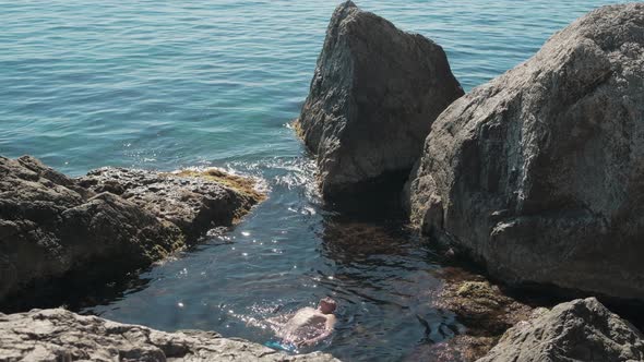 Tourists Swim in the Open Black Sea Among the Rocks on a Clear Sunny Summer Day alt