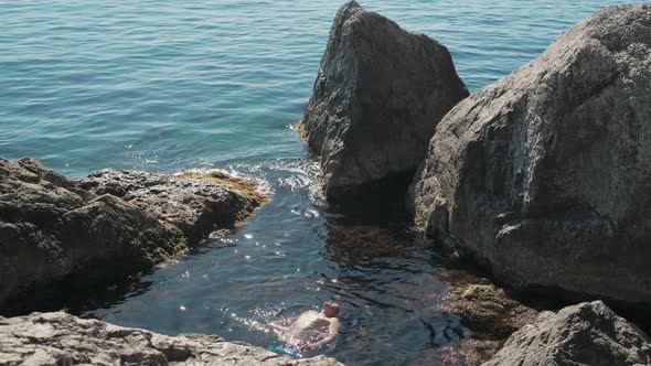 Tourists Swim in the Open Black Sea Among the Rocks on a Clear Sunny Summer Day