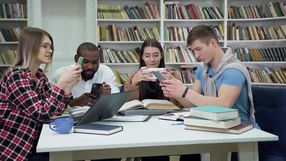 Friends Playing on their Phones During Break Between Preparation for Exams in the Library alt
