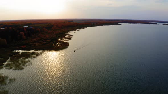 Aerial Footage of a Boat Sailing in a Lake at Sunset in Autumn