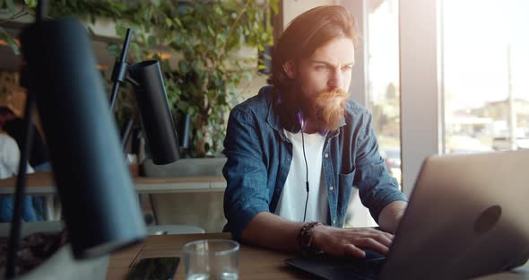 Man Working on Laptop Near Window