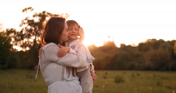 The Son Kisses His Mother Sitting at Sunset in a Field Hugging and Loving Mother alt