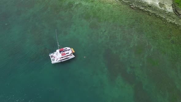 White Ship with Lowered Sails Drifts on Water of Clear Ocean alt