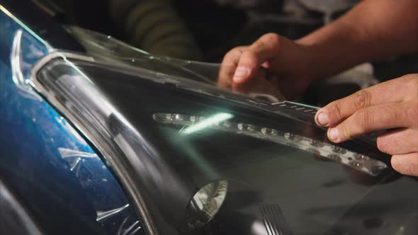 Close Up Shot of the Hands of a Man Who Cut the Vinyl Film on a Blue Car alt