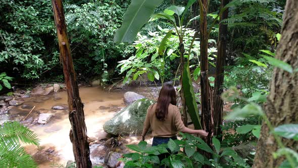 A female traveler walking into the waterfall in the forest