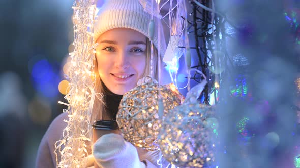 girl in a white hat looking at the camera and smiling near bright Christmas garlands