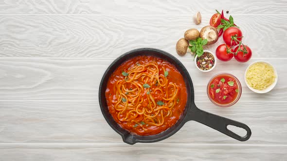 Cooking homemade pasta with tomato sauce in cast iron pan served with chili pepper, fresh basil