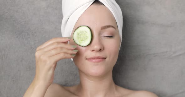 Portrait of a Young Beautiful Positive Smiling Woman with a Towel on Her Head Who Puts Cucumber