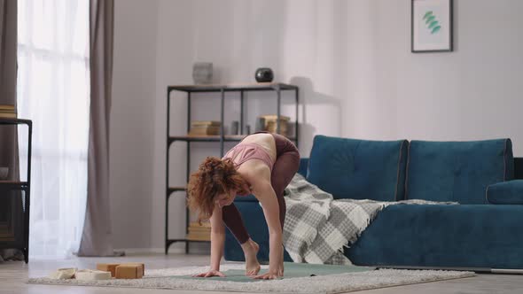 Woman is Doing Handstand During Home Yoga Training Performing Asana for Balance and Strength alt