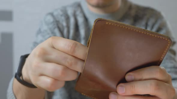 Male Get US Dollar Bills From Pocketsized and Foldable Wallet Made of Leather