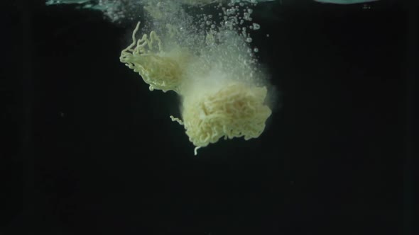 Slow Motion Close Up Of Noodles Being Dropped Into Water